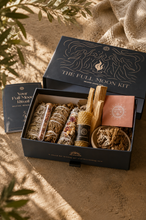 Load image into Gallery viewer, Full moon ritual kit open gift box with sage bundles, palo santo sticks, beeswax, rose of jericho candle and ritual guide in natural setting
