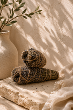 Load image into Gallery viewer, Egyptian wild lavender smudge stick from Saint Catherine, Sinai resting on a ceramic plate surrounded by dried flowers — ethically harvested for calming rituals

